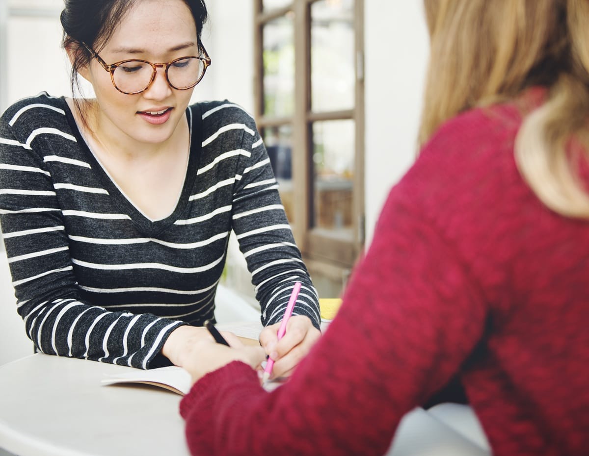 A person sitting at a table with a health professional, focused on filling out the NDIS Access Request Form (ARF)