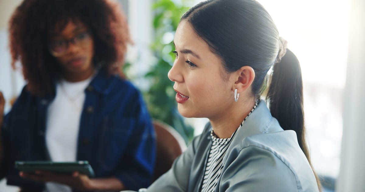 A young woman speaking and explaining information, representing a support coordinator helping a client navigate their plan.