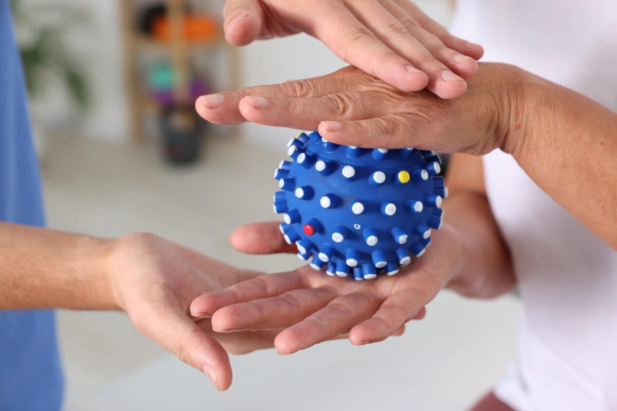 Occupational therapist and client holding a blue textured sensory ball, demonstrating tactile therapy methods.